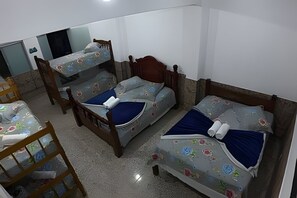 Una habitación con tres literas, una silla de madera y una mesita.