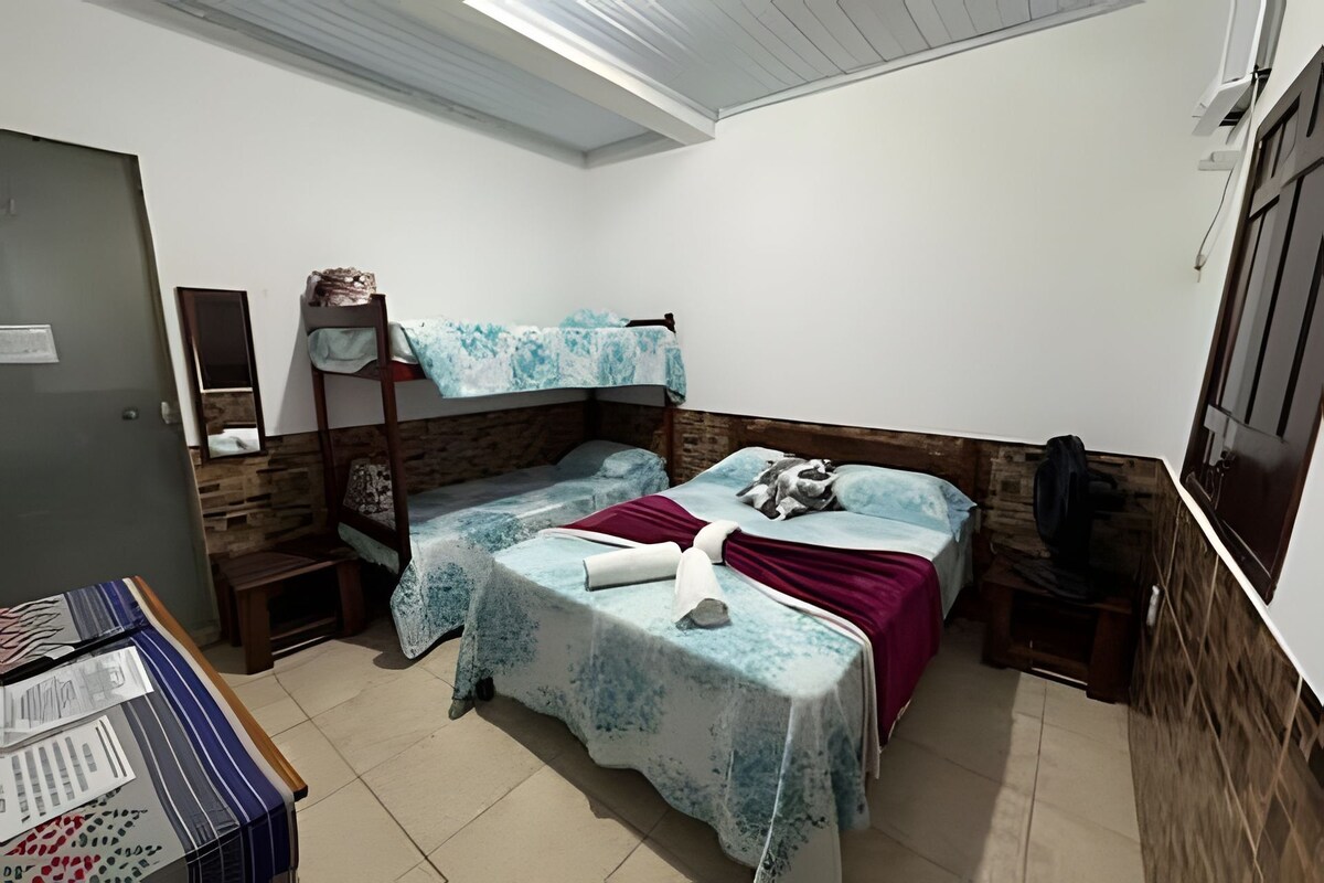 A small, compact room with two single beds, a wooden headboard, a small table with a chair, and a wardrobe.
