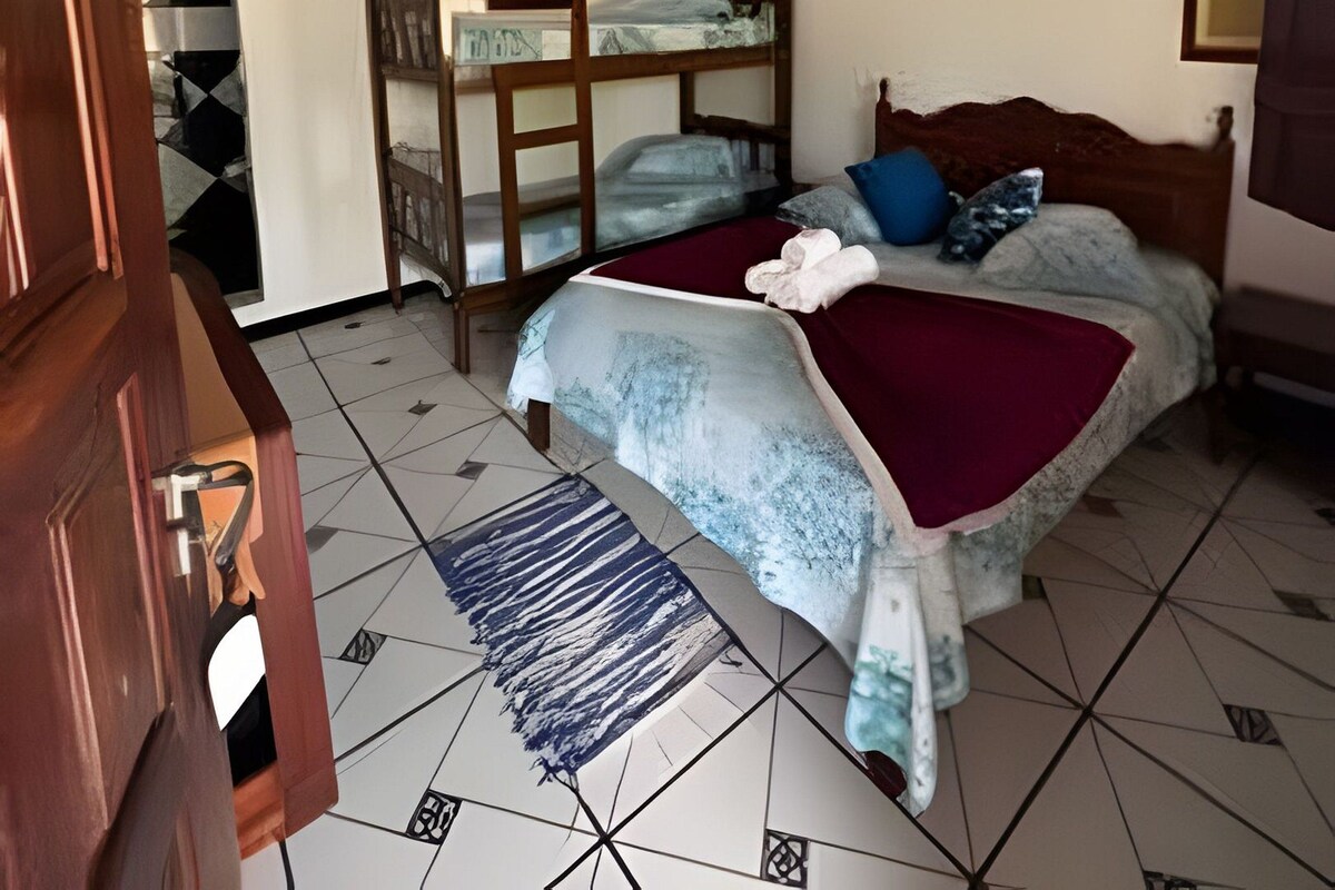 A bedroom with a bunk bed, a ceiling fan, and a bed with a red blanket.