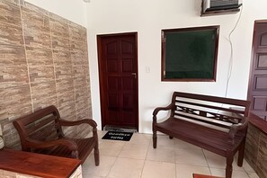 Una habitación con un banco de madera, una puerta y un aire acondicionado instalado en la pared.