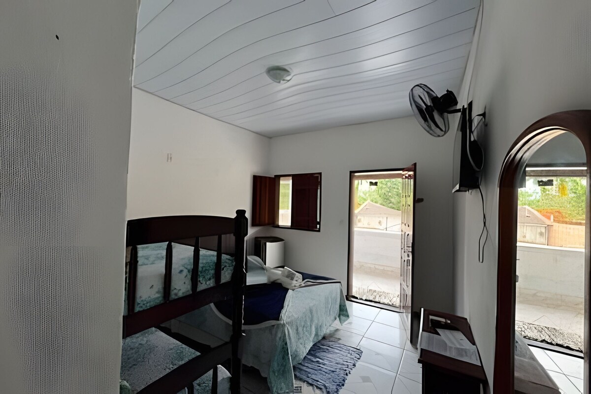A bedroom with a bed, a bedside table, a window, and a door leading outside.