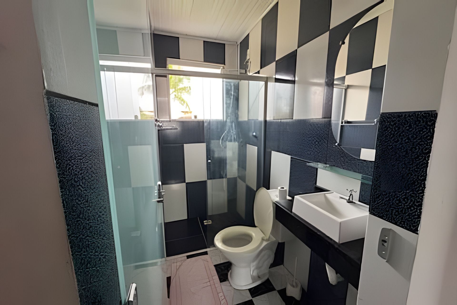 Een badkamer met een douchecabine van glas, een toilet en een wastafel.