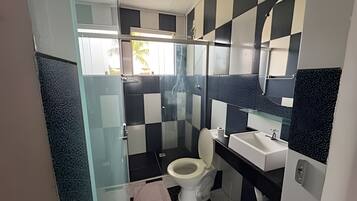 Een badkamer met een douchecabine van glas, een toilet en een wastafel.