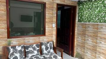 Quarto com um banco, uma janela grande e uma porta que dá para outro espaço.