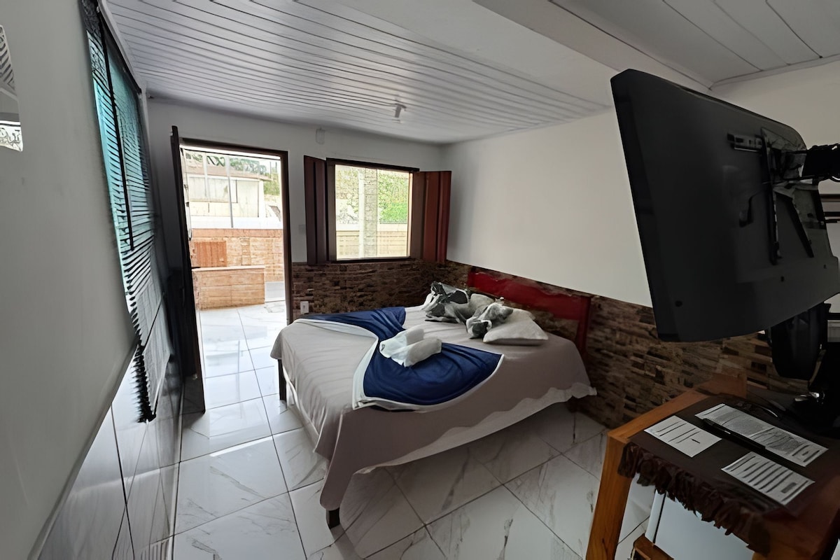 A bedroom with a bed, a desk, and a view of the outside.