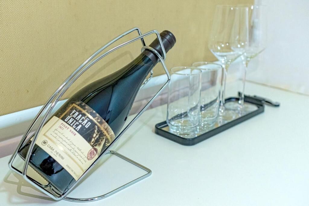 Una botella de vino sobre un soporte, junto con copas y una bandeja.