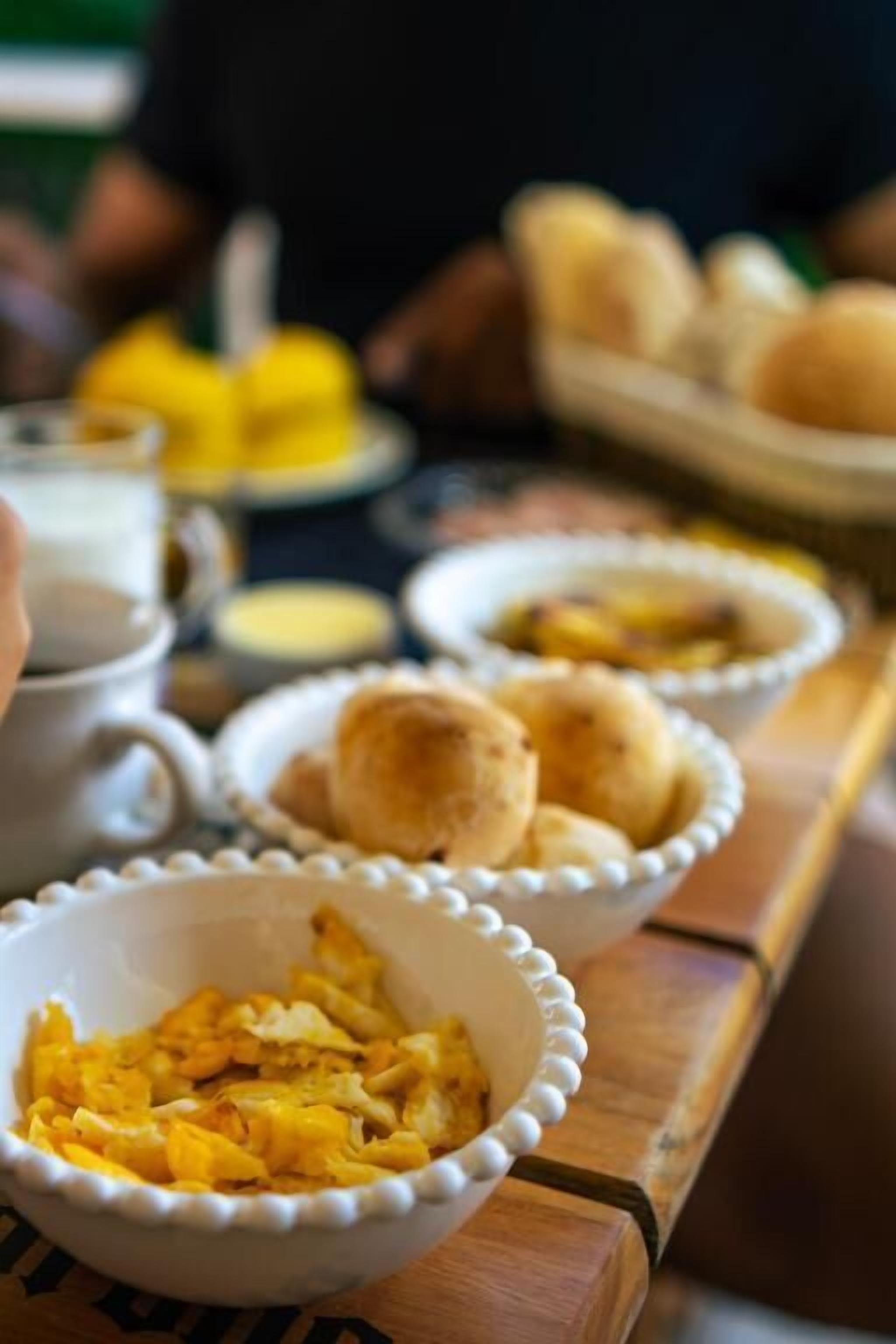 A dining table with various dishes including scrambled eggs, bread rolls, and a cup of coffee.