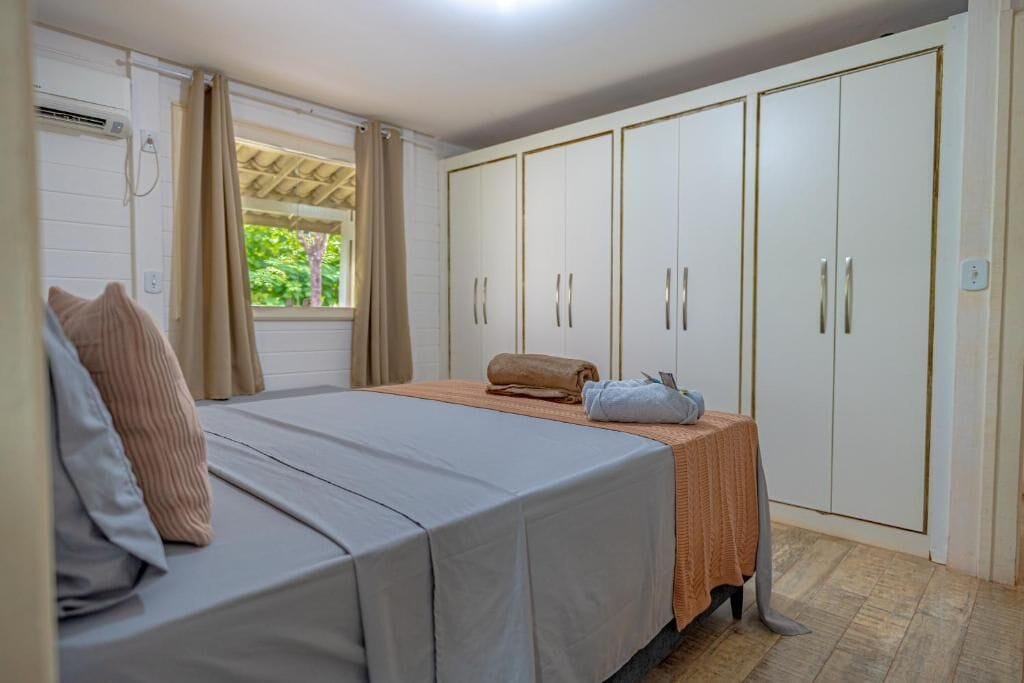 A bedroom with a bed, a wardrobe, and a window with curtains.