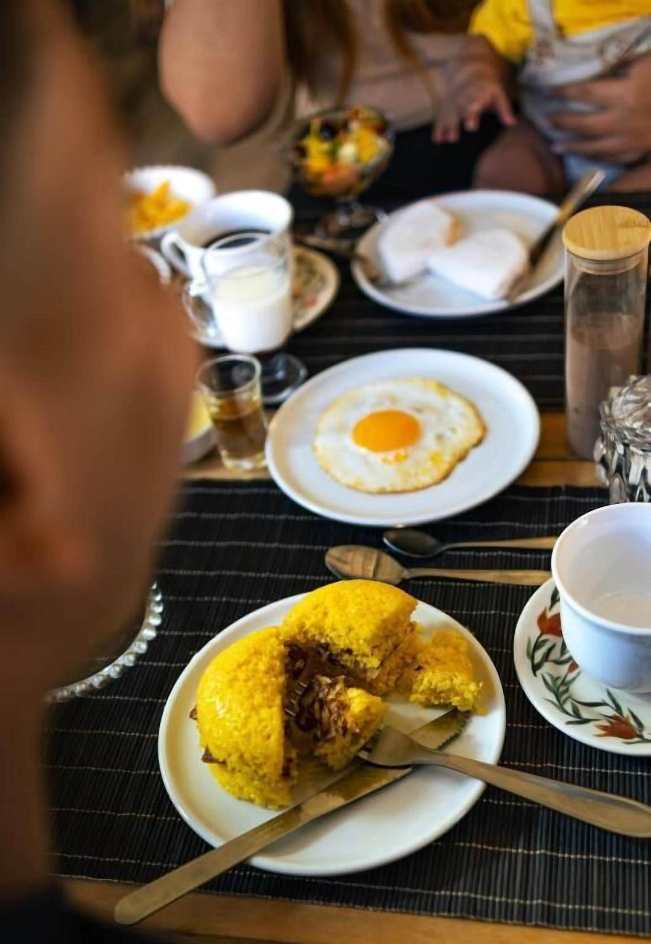 A dining table with plates of food, including a fried egg and a yellow dish, possibly a breakfast item.
