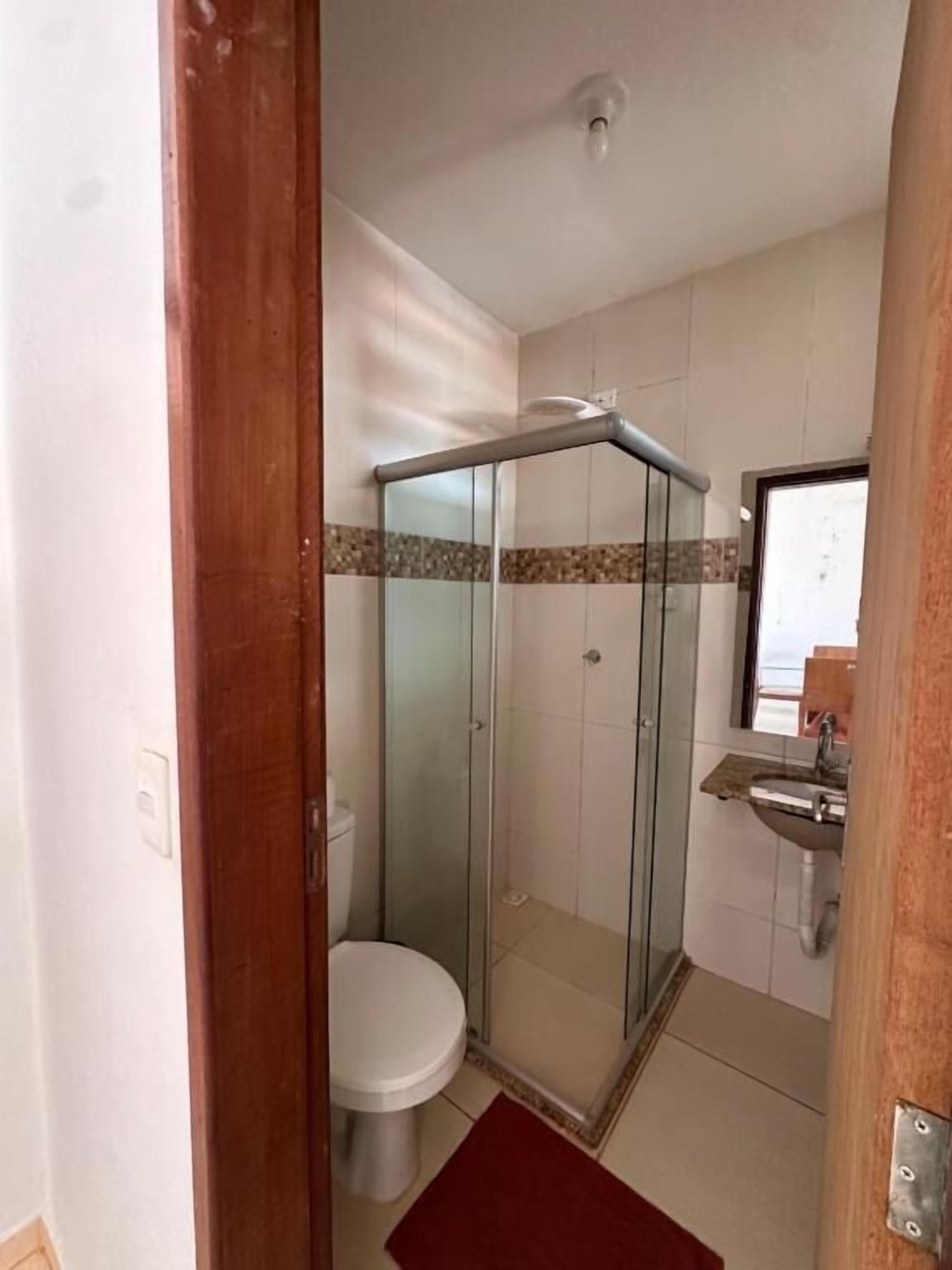 A bathroom with a glass-enclosed shower, a toilet, and a sink.