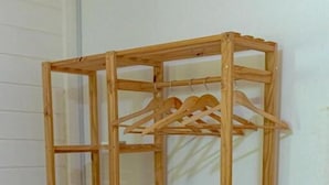 Un estante de madera con varios compartimentos y una barra colgante.