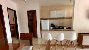 Una sala de estar moderna con comedor, una cocina al fondo y un separador de vidrio.