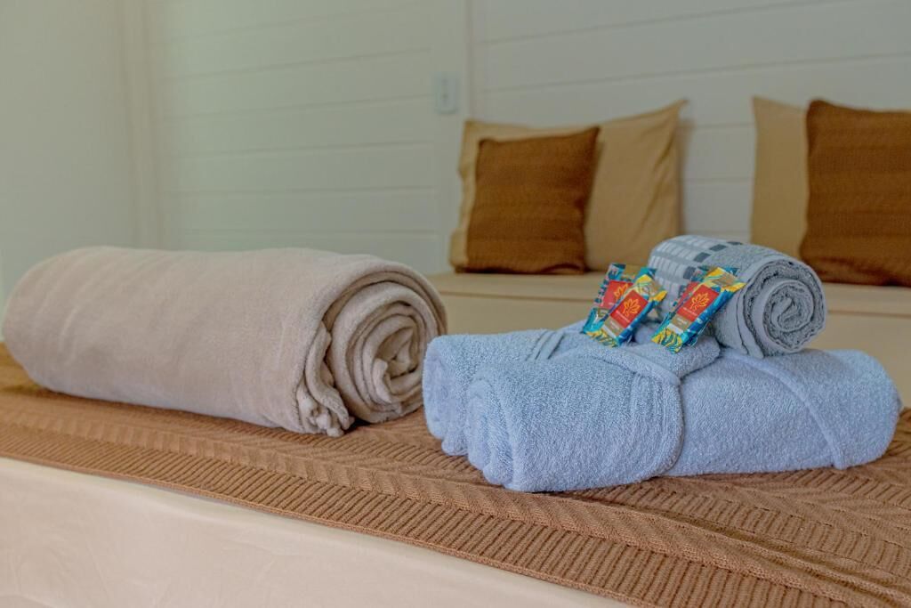 A bed with rolled towels and a patterned blanket.