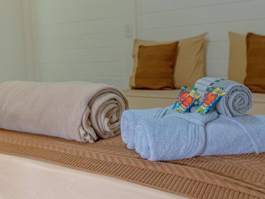 A bed with rolled towels and a patterned blanket.