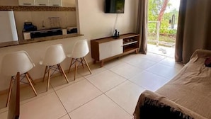 Habitación de hotel con cama, televisión, kitchenette y balcón.