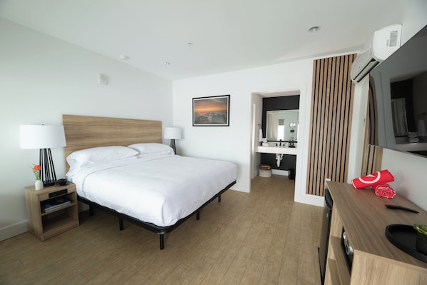 Ein modernes Hotelzimmer mit einem großen Bett, Nachttischen, einem Schreibtisch und einem Spiegel.