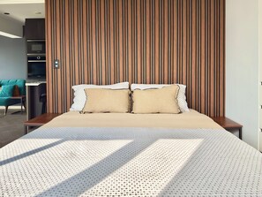 A modern bedroom with a large bed, a wooden slatted headboard, and a television in the corner. - Luxury Apartment with nice view (Jesús María)