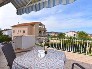 Una terrazza con un tavolo imbandito per due persone, una sedia e vista su un edificio con un balcone.