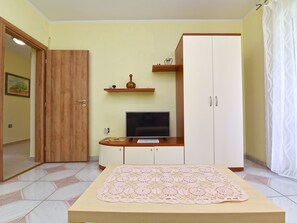 A bedroom with a bed, a TV, a wardrobe, and a small shelf with decorative items. - Apartment 372 by Interhome (Medulin)