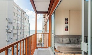Un balcón con vista al mar, un sofá y una pared con cuadros enmarcados.