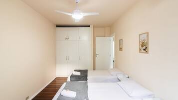A hotel room with two beds, a ceiling fan, and a wardrobe.