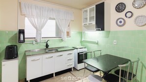 A compact kitchen with a sink, stove, and a dining table with chairs. - Apart w/ Side sea View, 50m From the Beach Mrd0061 (Balneário Camboriú)