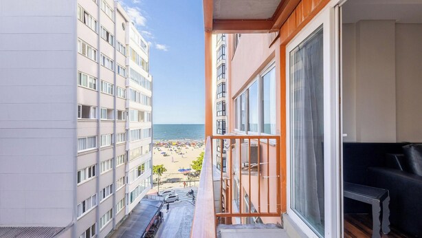 Ein Balkon mit Blick auf einen Strand und angrenzende Gebäude.