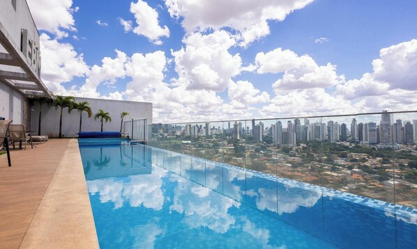 A rooftop pool with a city view, palm trees, and a modern building facade. - Full Studio in Jardim Goias Msst1001 (Goiânia)