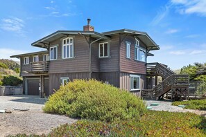 A two-story house with a covered porch and a staircase leading to the upper level. - Miwok Escape, by Vinifera Homes (Bodega Bay)