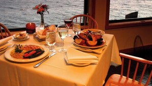 A table set for dining with a view of the sea, a vase with flowers, and a candle. - Miwok Escape, by Vinifera Homes (Bodega Bay)