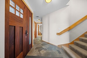 A hallway with a wooden door, a staircase, and a stone floor. - Miwok Escape, by Vinifera Homes (Bodega Bay)