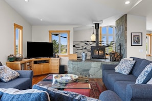 A living room with a fireplace, a television, and seating. - Miwok Escape, by Vinifera Homes (Bodega Bay)