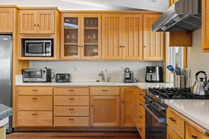 A kitchen with wooden cabinets, a microwave, a toaster, a coffee maker, and a kettle. - Miwok Escape, by Vinifera Homes (Bodega Bay)