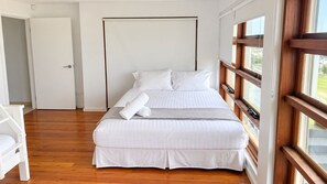 Ein Schlafzimmer mit einem Bett, einer weißen Tür und einem Fenster mit Blick.