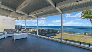 A covered outdoor seating area with a view of the beach and ocean. - Dea-Del-Mare 6BR Sleeps 18 Beach Front (The Entrance North)