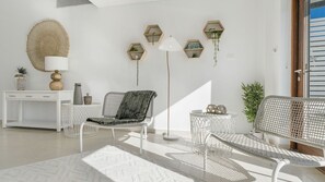A modern living room with a white sofa, a round coffee table, and a floor lamp. There are hexagonal shelves on the wall and a white desk with drawers. - Dea-Del-Mare 6BR Sleeps 18 Beach Front (The Entrance North)