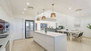A modern kitchen with a central island, pendant lighting, and a dining area with a TV.