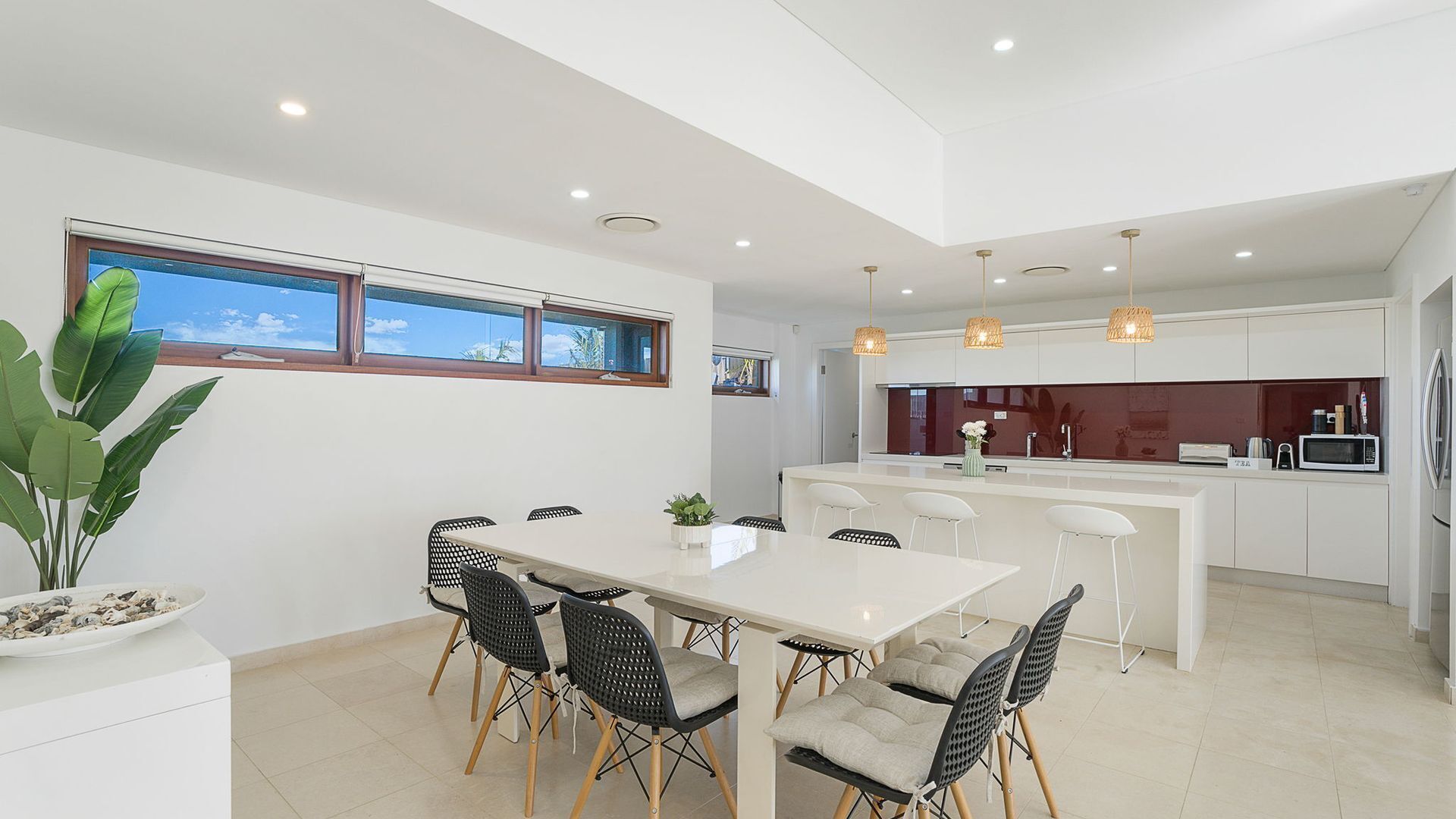 A modern kitchen with white cabinetry, a central island, and pendant lighting.