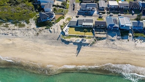 Eine Luftaufnahme einer Küstenwohngegend mit Häusern, einem Strand und freiem Blick auf den Ozean.
