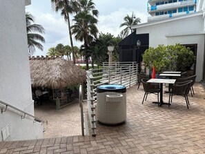 A patio area with a thatched-roof structure, outdoor seating, and a hot tub. - Oceanfront Sunrise Escape Condo | Beach and Pool (Fort Lauderdale)