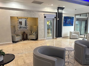 A lobby with a marble floor, seating areas, a reception desk, and a large mirror. - Oceanfront Sunrise Escape Condo | Beach and Pool (Fort Lauderdale)