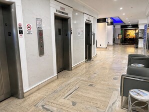 A hotel corridor with elevators, a reception area, and seating. - Oceanfront Sunrise Escape Condo | Beach and Pool (Fort Lauderdale)