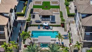 A rooftop pool area with lounge chairs and umbrellas, surrounded by residential buildings. - Downtown Naples Escape | Resort Pool | Luxury Condo (Naples)