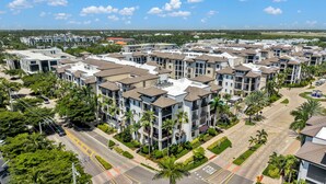 A residential complex with multiple apartment buildings, a central road, and surrounding greenery. - Downtown Naples Escape | Resort Pool | Luxury Condo (Naples)
