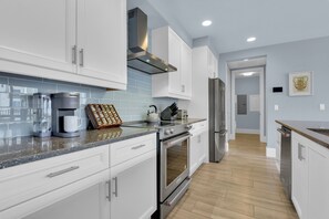 A modern kitchen with white cabinets, stainless steel appliances, and a tiled backsplash. - Downtown Naples Escape | Resort Pool | Luxury Condo (Naples)
