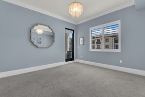 A room with a large mirror, a chandelier, and a window with a view of buildings. - Downtown Naples Escape | Resort Pool | Luxury Condo (Naples)