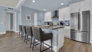 A modern kitchen with a large island, stainless steel appliances, and a seating area with bar stools. - Downtown Naples Escape | Resort Pool | Luxury Condo (Naples)