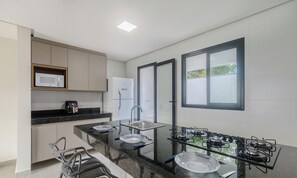 Een moderne keuken met een zwart aanrecht, roestvrijstalen apparatuur en een raam met uitzicht.