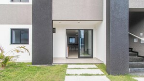 A modern building with a glass entrance, a visible kitchen area, and a staircase leading to an upper level. - Apart in Condo w/ Barbecue 700m From Beach Nvm0009 (Porto Seguro)