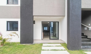 Een modern gebouw met een plat dak, grote glazen deuren en een zichtbaar interieur met een eetgedeelte.